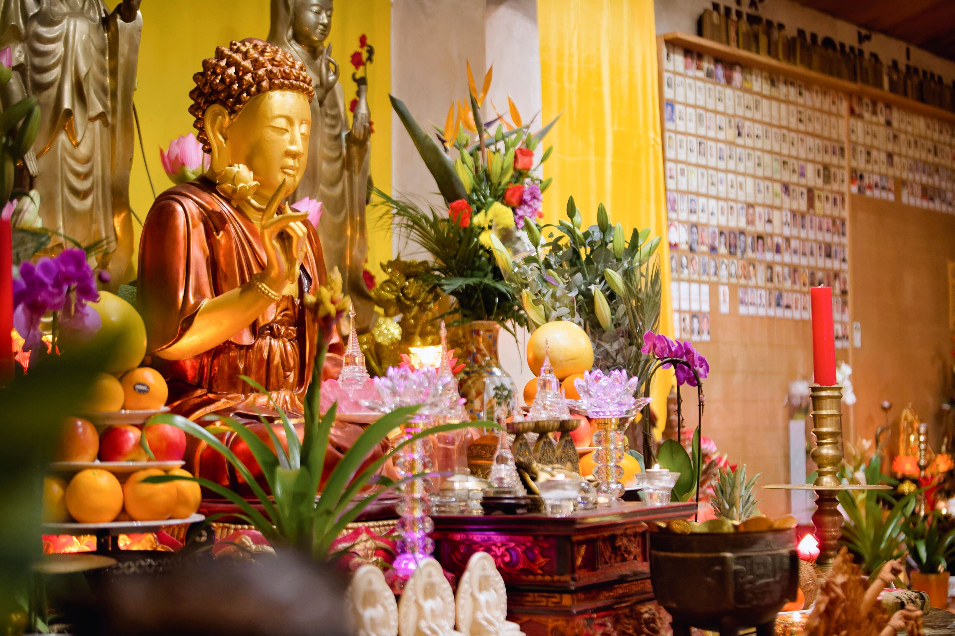 A golden Buddha statue surrounded by flowers and candles in a temple.