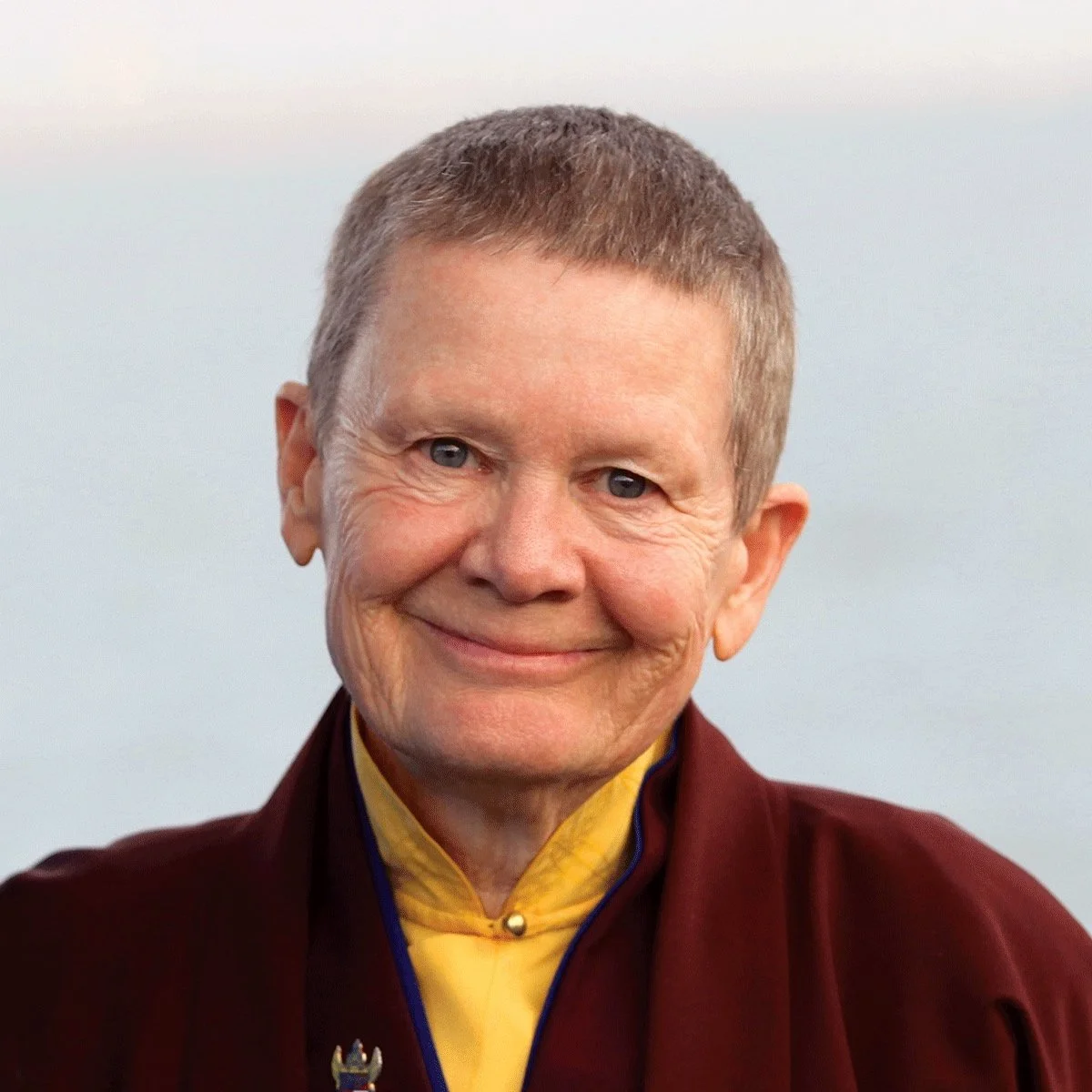 Smiling person in maroon and yellow clothing.