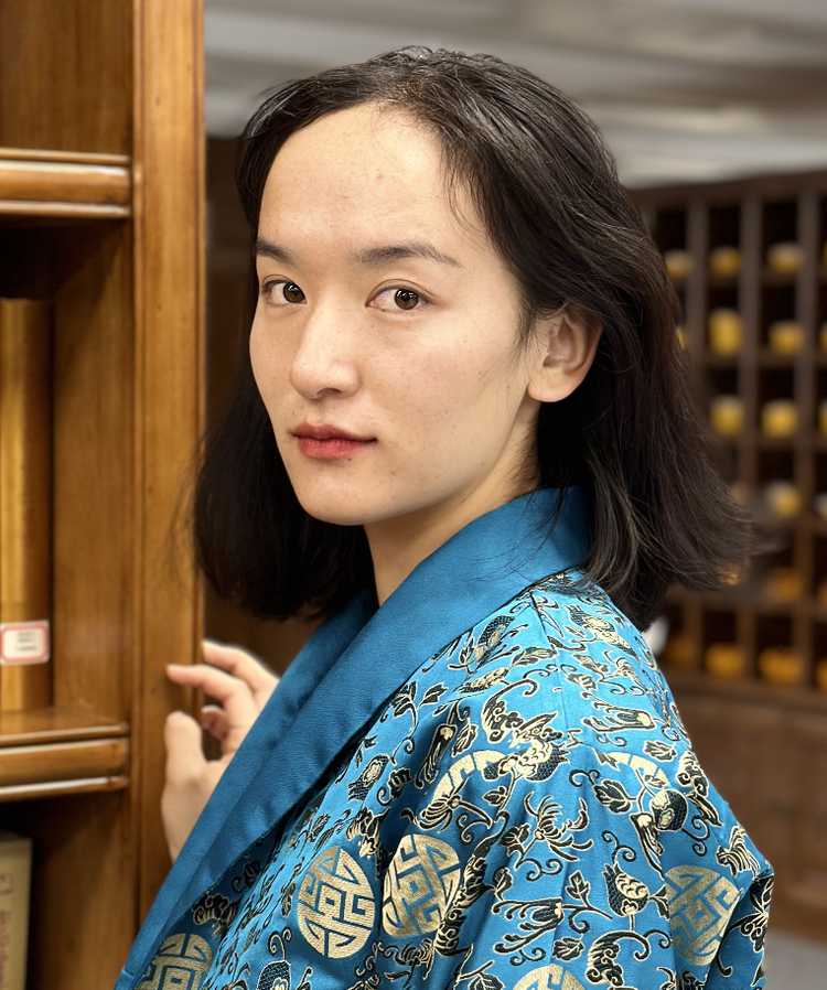 Person in blue robe beside wooden shelves.