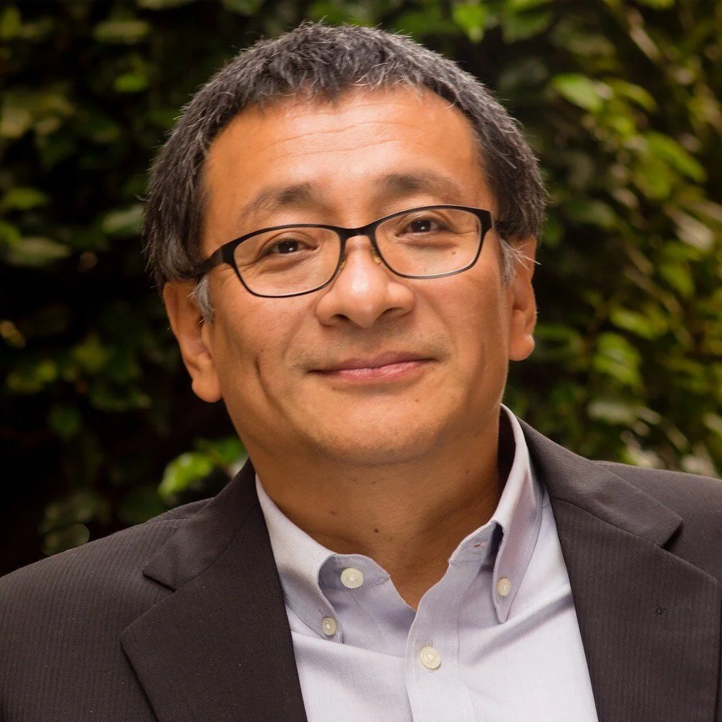 Man smiling with glasses and suit.