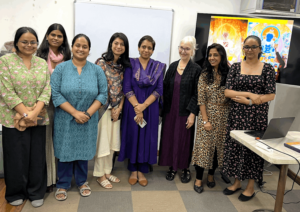 Group of women standing together in a room, smiling at the camera.