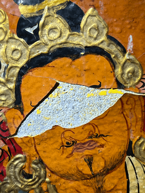 Close-up of a traditional painting showcasing a face with intricate golden headgear.