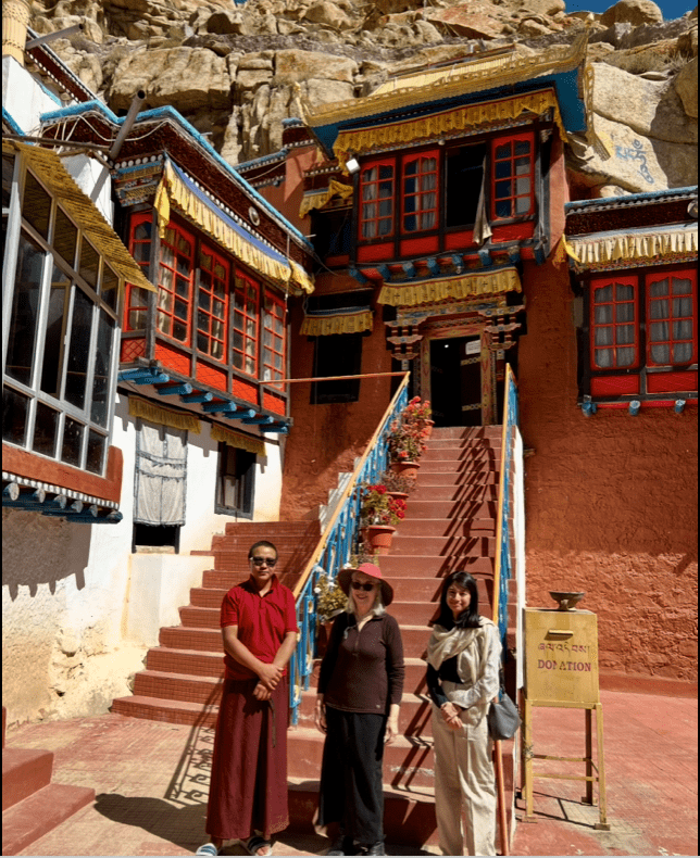 Three people standing in front of a colorful, ornate building with stairs.