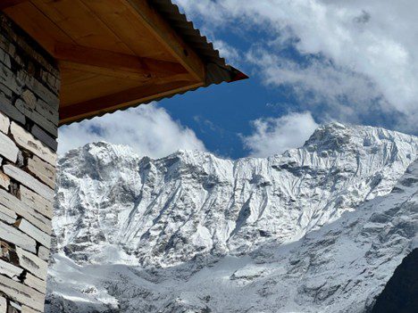 Snow-covered mountain peaks under a blue sky with clouds.