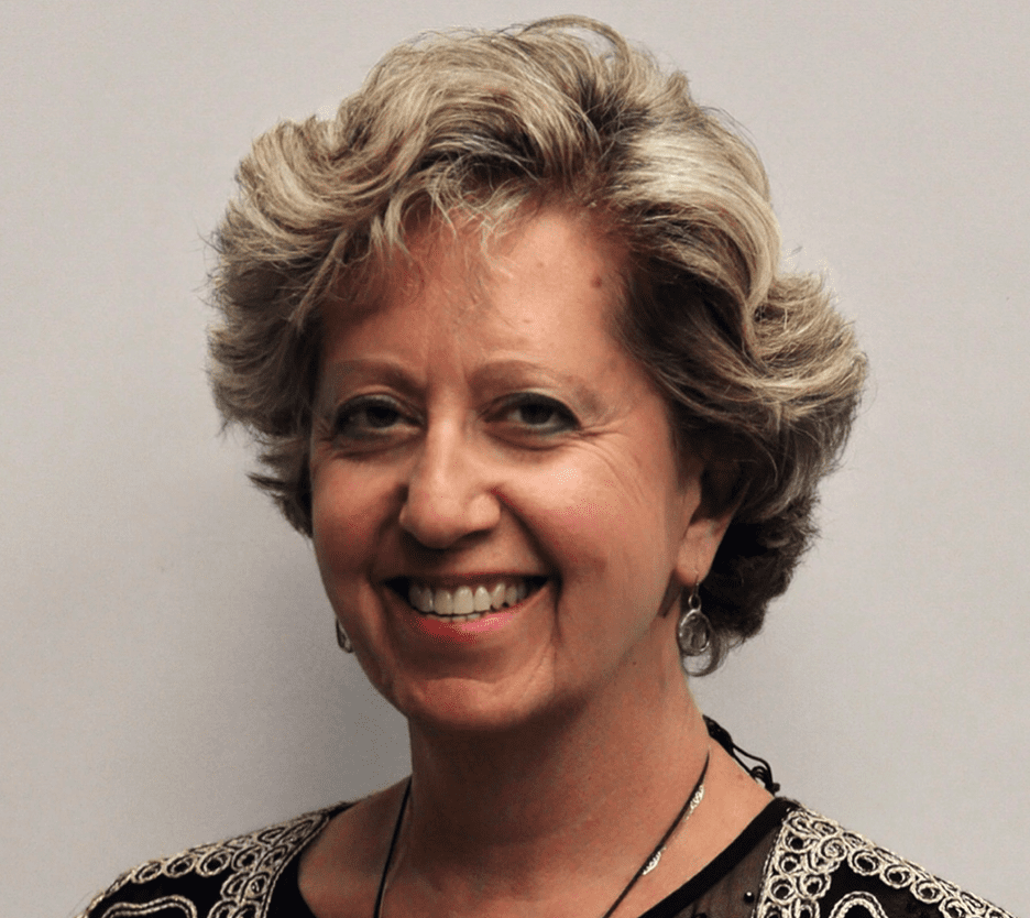 Smiling woman with curly blonde hair and patterned top.