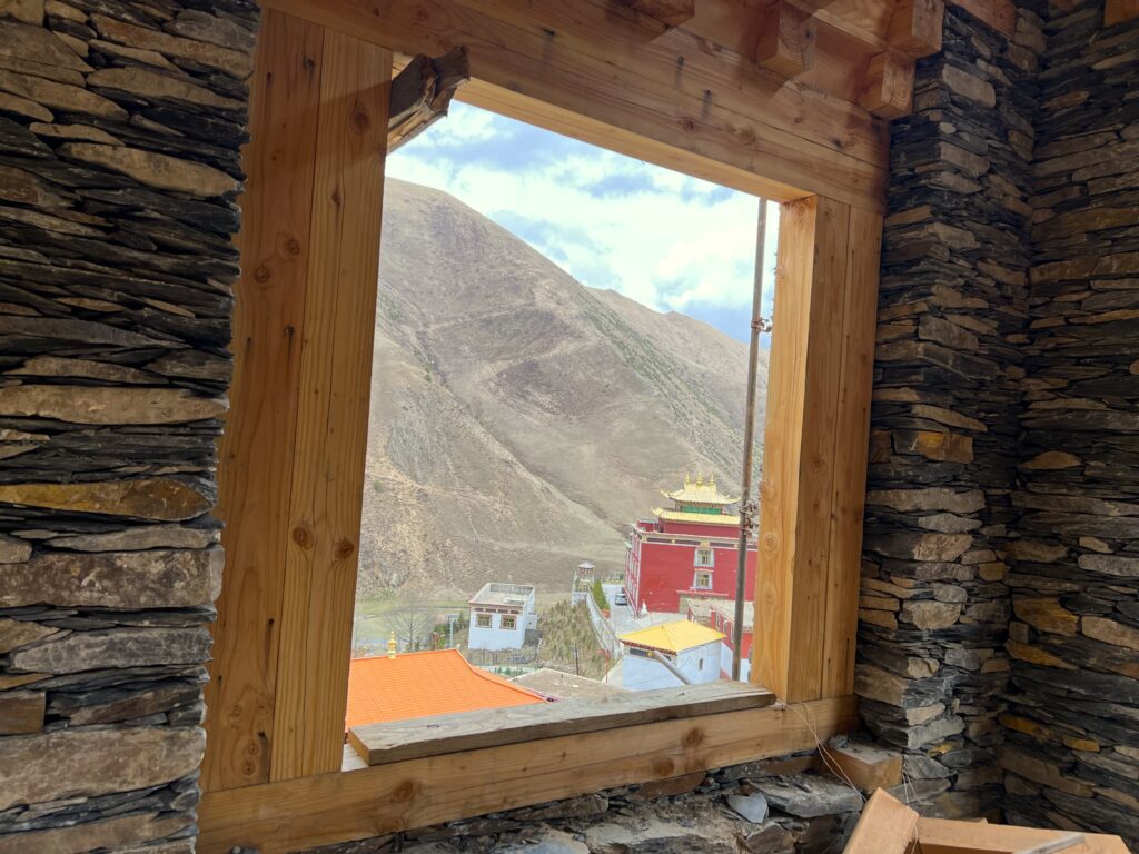 View of a mountain and colorful buildings through a rustic wooden window.