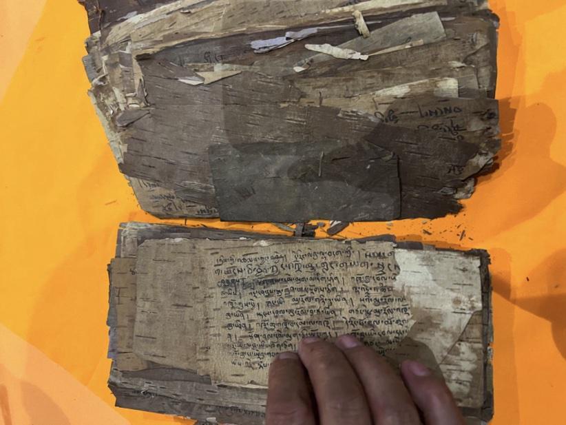 Ancient, worn manuscript with handwritten text on fragile pages.