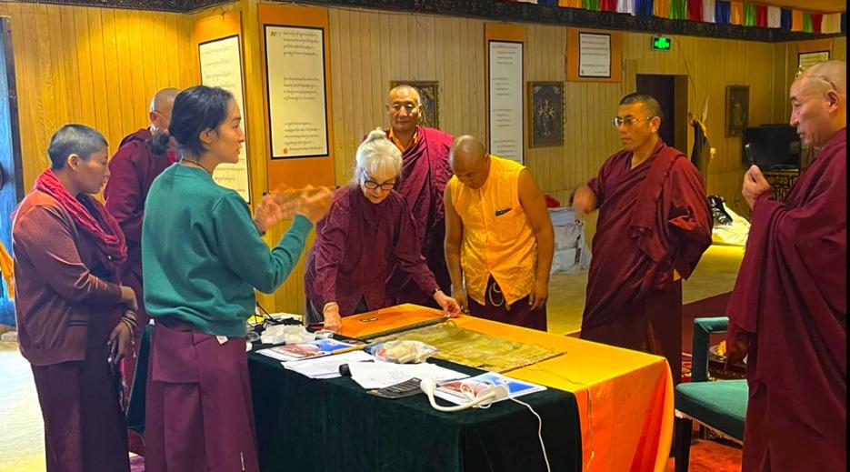 A group of monks and a man gathered around a table with religious texts.