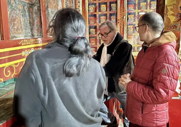Three people observing colorful wall paintings.