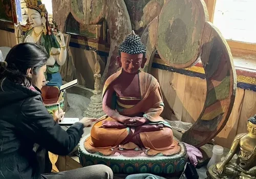 Person restoring a Buddha statue indoors.