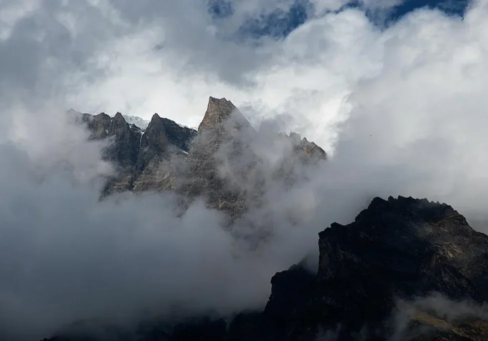 Cloud-covered mountain peaks under a blue sky.