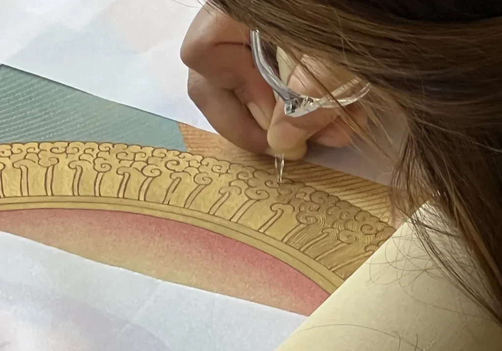 Person painting intricate gold design pattern.