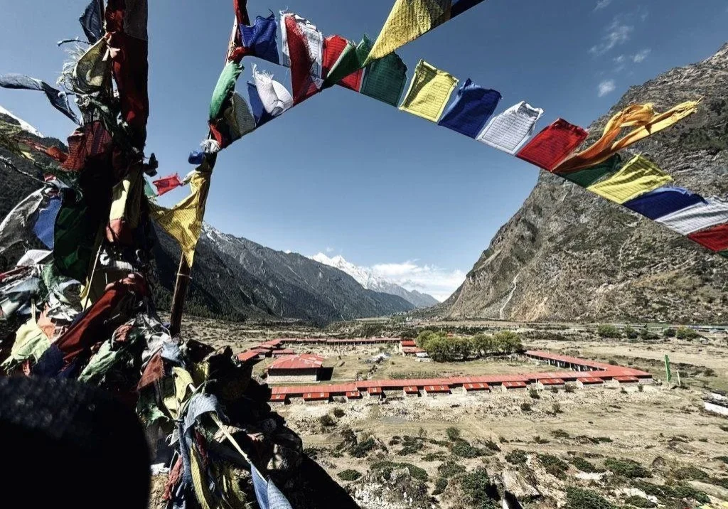 Colorful prayer flags with mountainous landscape.
