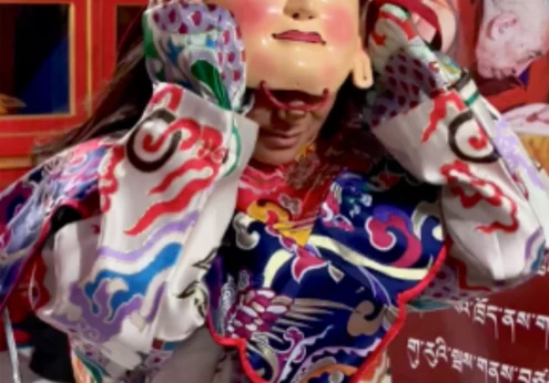 Person in colorful traditional costume and mask.