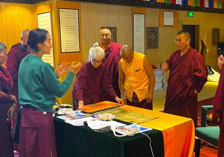 A group of monks and a man gathered around a table with religious texts.